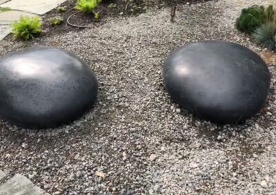 Black sculptural rocks made from glass fiber reinforced concrete. Used as covers for utility covers in a backyard in the Hamptons New York.